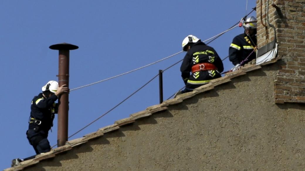 Hasiči připevňují komín na střechu Sixtinské kaple, který bude signalizovat zvolení či nezvolení papeže
