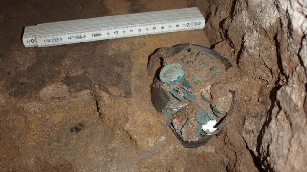 Částečně odkrytý hrnek s mincemi v bošileckém kostele před tím, než jej archeologové vyzvedli