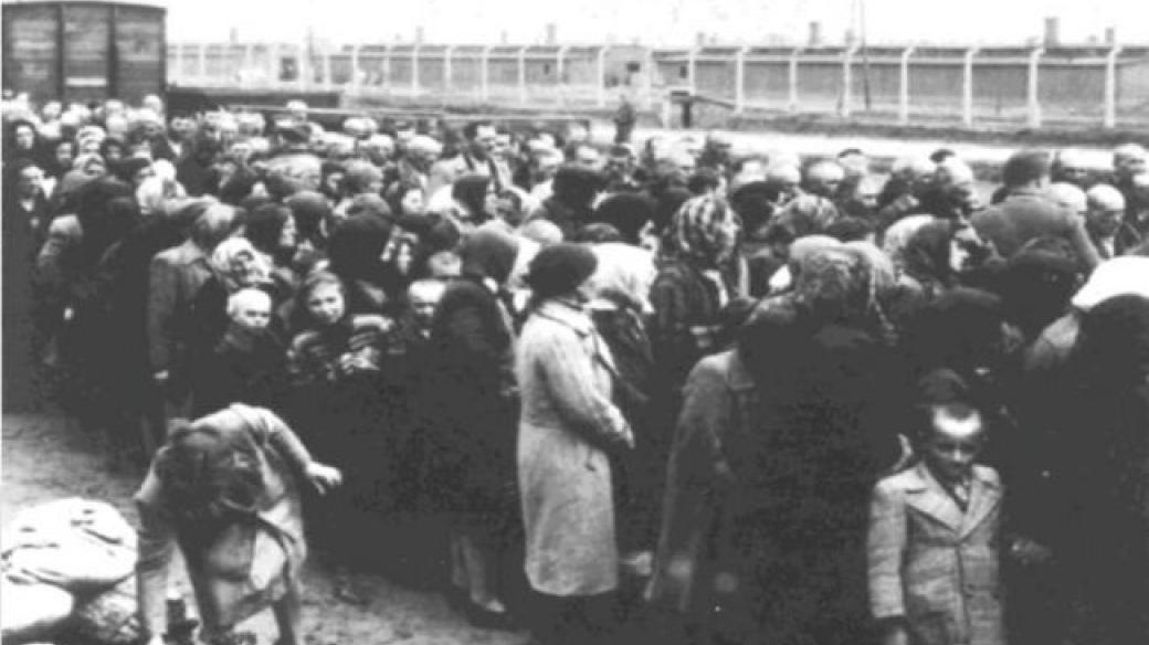 Židovské ženy a děti před selekcí na rampě v Osvětimi-Březince. V pozadí jsou baráky sektoru BIa (rok 1944)