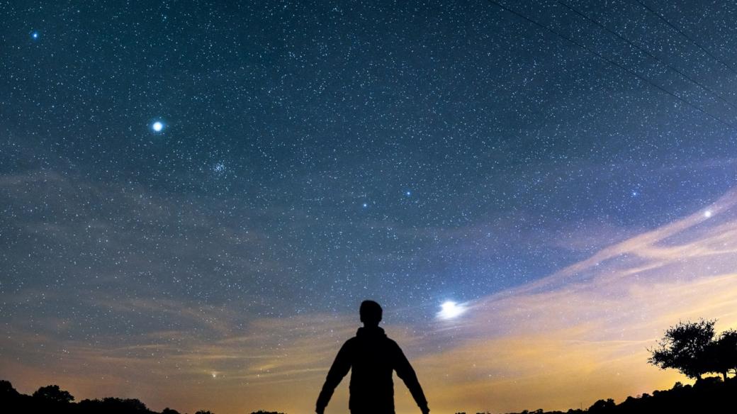 Noční obloha se souhvězdím Blíženců. Dva jasnější body nad hlavou pozorovatele jsou hvězdy Castor a Pollux