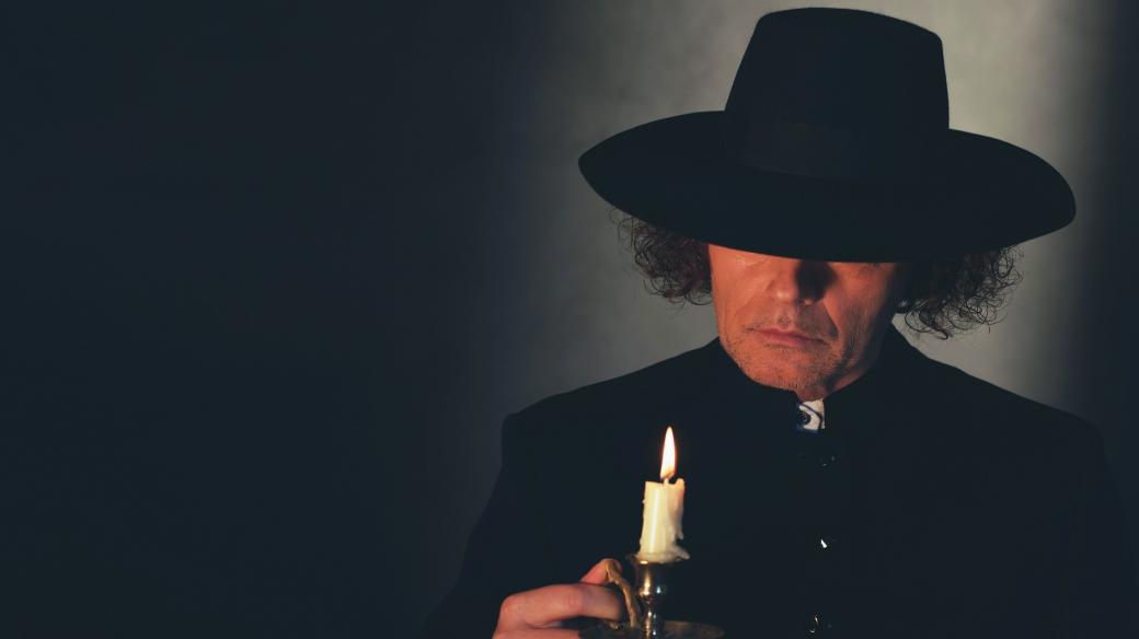 Kněz v širokém klobouku a se svíčkou v ruce