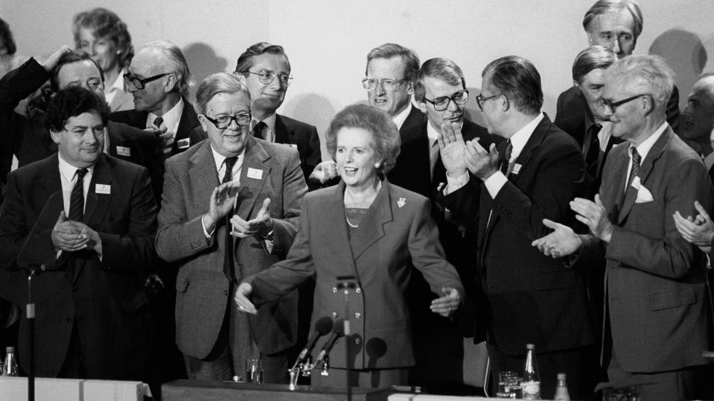 Margaret Thatcher při projevu sklízí aplaus kolegů z kabinetu na konferenci Konzervativní strany (13. října 1989)
