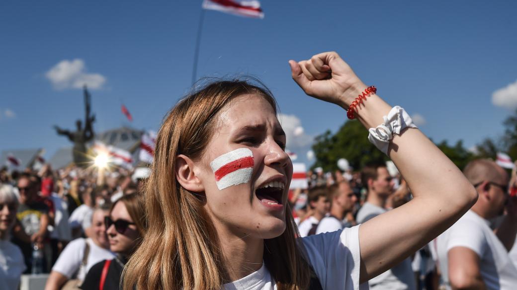 Bělorusko a protesty v ulicích (A woman Belarus opposition supporter with a drawing of a former white-red-white flag of Belarus used in opposition to the government punches the air during a demonstration in central Minsk on August 16, 2020)