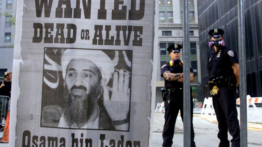 Policisté stojí vedle plakátu, na kterém je vyhlášeno pátrání po Usámu bin Ládinovi