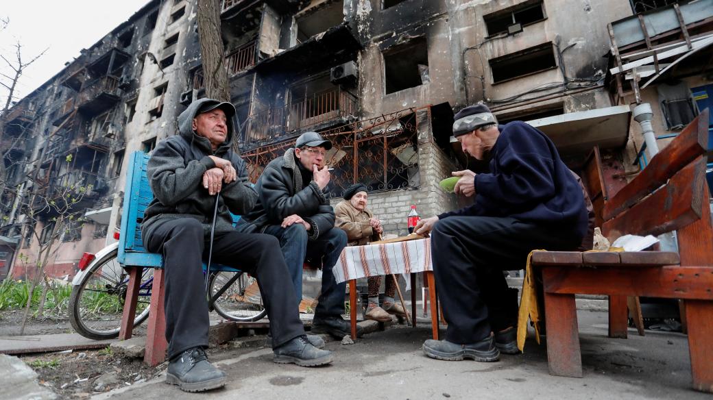 Obyvatelé Mariupolu sedí před zničenou budovou