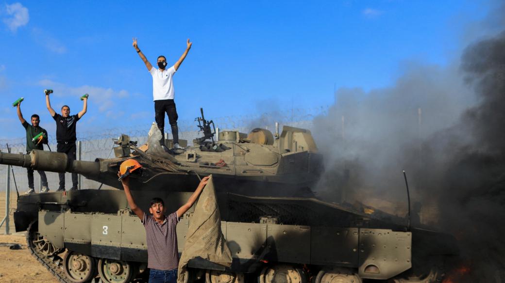 Palestinci oslavují hořící izraelské vojenské vozidlo zasažené palestinskými ozbrojenci, kteří pronikli do oblastí jižního Izraele