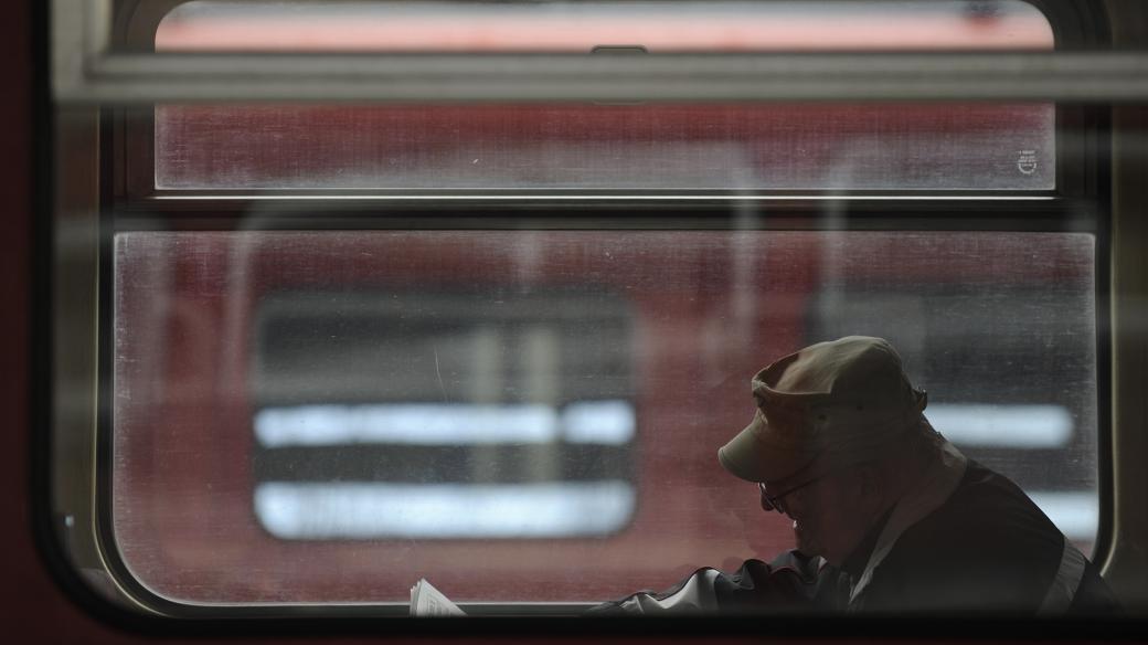 Muž sedí u okna ve vlakovém kupé