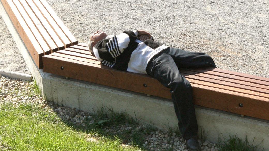 Bezdomovec spí na lavičce