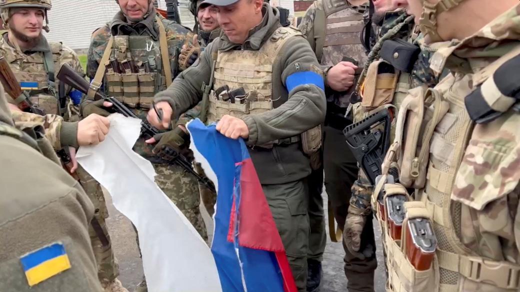 Vjačeslav Zadorenku rozřezává ruskou vlajku ve městě Kozača Lopan v Charkovské oblasti