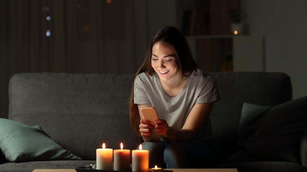 Žena píše zprávu na telefonu při svíčkách