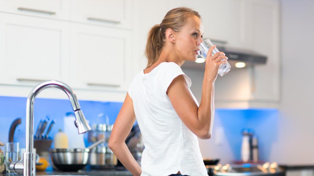Žena se sklenicí vody v kuchyni