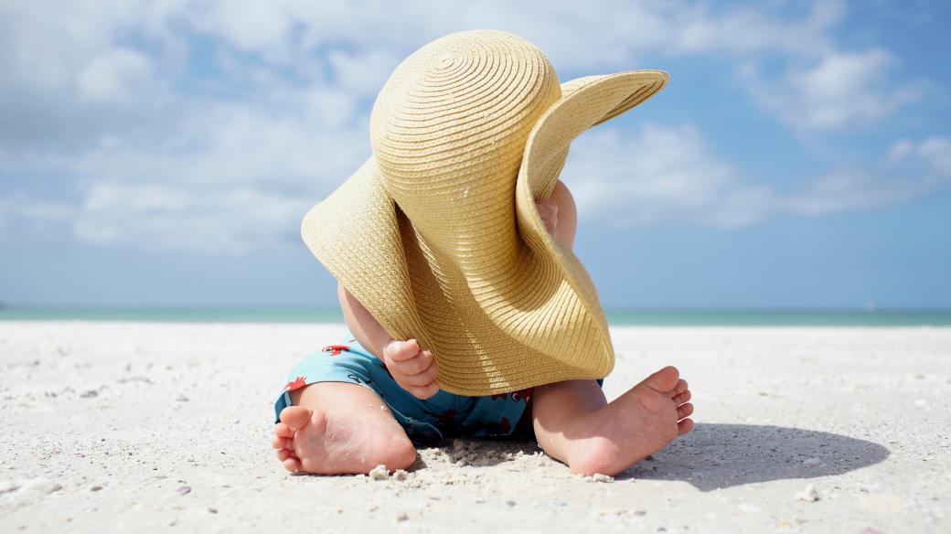 Chlapec si hraje s kloboukem na pláži