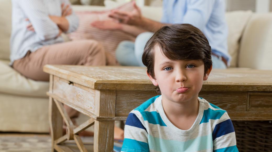 Smutný chlapec poslouchá hádku rodičů
