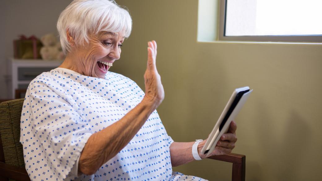 Starší žena v nemocnici používá tablet k videohovoru