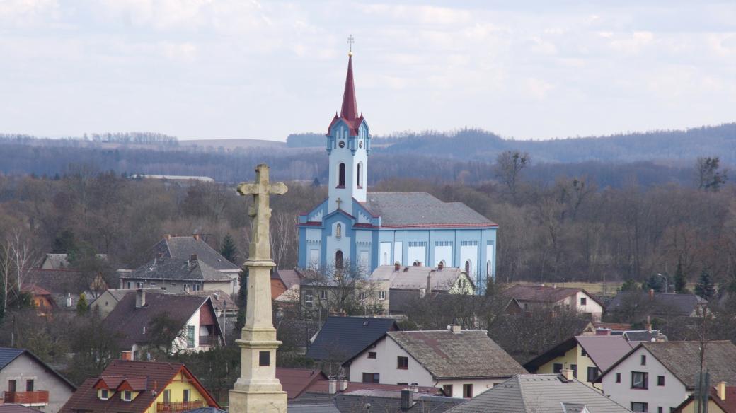 Kříž nad obcí připomíná padlé v bitvě u Zvole, v pozadí kostel Neposkvrněného početí panny Marie z roku 1866