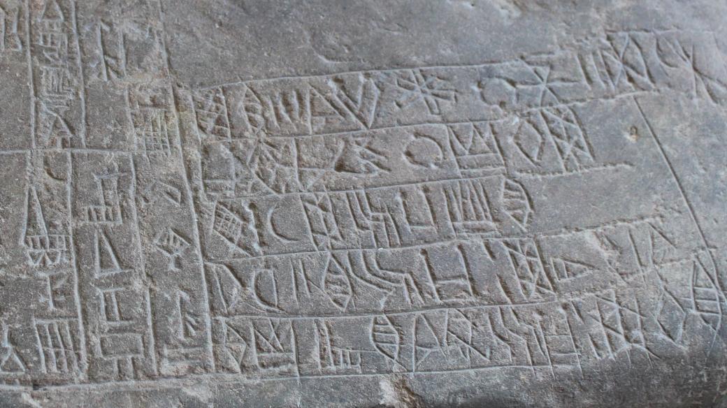 Detail dvojjazyčného nápisu na kameni se lví hlavou z lokality Súsy v dnešním Íránu. Vlevo část nápisu v akkadštině, vpravo nápis v elamském lineárním písmu. Konec 23. stol. – 22. stol. př.n.l.