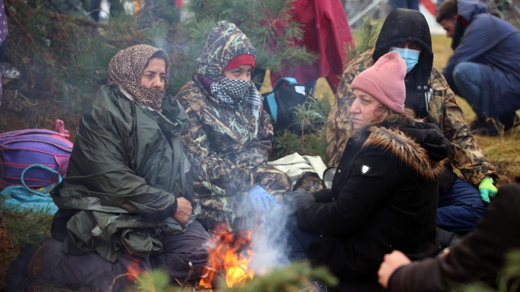 Skupina žen na bělorusko-polské hranici se snaží zahřát u ohně