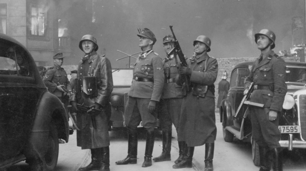 Generál SS Jürgen Stroop (druhý muž zleva s polní čepicí) a jeho muži pozorují hořící domy ve varšavském ghettu