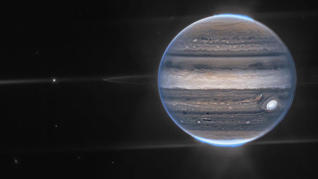Jupiter na snímku dalekohledu Jamese Webba. Vidět jsou i slabé prstence planety, polární záře na obou pólech a dva malé měsíce – Amalthea a Adrastea