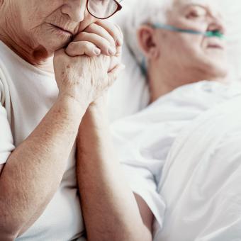 Partnerka drží muže za ruku v hospici
