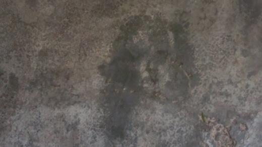 Jedna z tváří na podlaze domu – ženský obličej s hustými vlasy