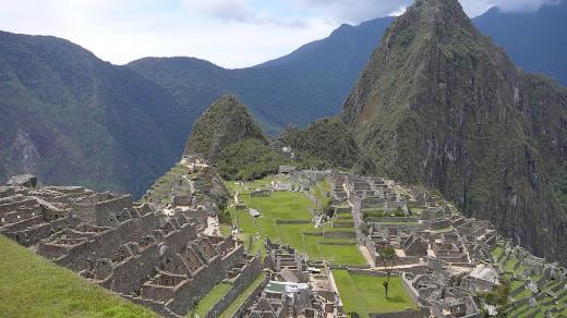 Machu Picchu (kečujsky Stará hora) s branou na inckou stezku za zády, uprostřed posvátné místo, v pozadí Wayna Picchu (kečujsky Mladá hora)
