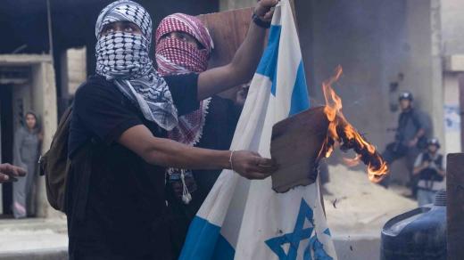 Mladí Palestinci při demonstranci pálí izraelskou vlajku