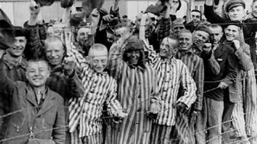 Osvobození vězni v Dachau mávají americkým vojákům