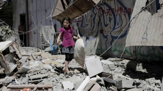 Palestinská dívka sbírá věci své rodiny v domě, který byl zasažen při raketovém útoku v Gaze 