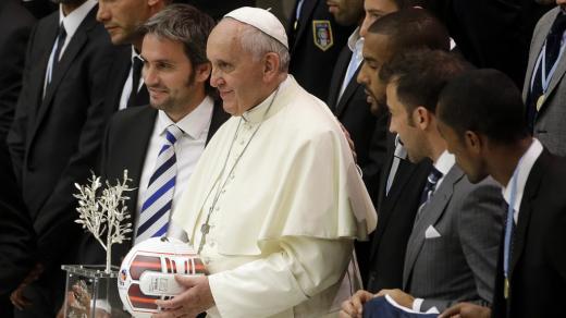 Papež František s fotbalovým míčem a s hráči, kteří se 1. září 2014 utkali v mezináboženském zápase za mír v hale Pavla VI. ve Vatikánu