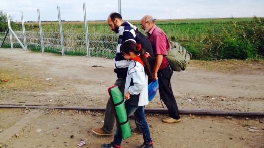 Migranti v Röszke na maďarsko-srbské hranici - cesta skrz plot
