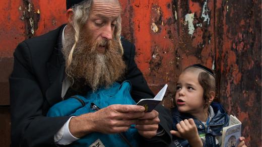 Z výstavy Svět, který měl zmizet: Chasidští poutníci v Umanu na Ukrajině. Otec se synem čtou žalmy u hrobky rabi Nachmana. Hasisic pilgrims in Uman in Ukraine
