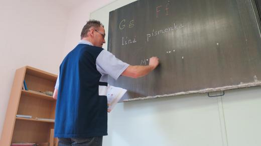 Učitel Jan Hruban seznamuje dva žáky první třídy s novými písmeny