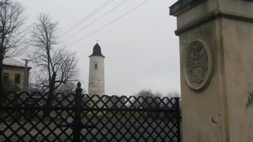 Historická brána v pozadí s Hláskou a zchátralým zámkem