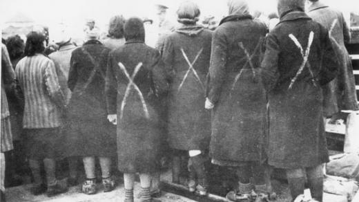 Ženy z koncentračního tábora Ravensbrück shromážděné potom, co do tábora dorazil Červený kříž v roce 1945. Bílá značka znamená, že jde o vězně, ne o civilisty