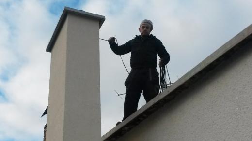 Kominík Jakub Kůta pracuje na střeše