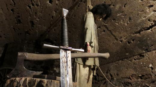 Figurina odsouzence a katovský meč v popředí