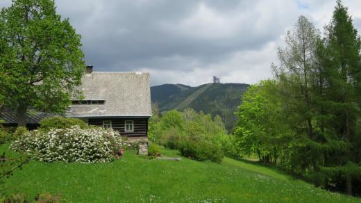 Roubená chalupa v částí Horní Morava, v pozadí Stezka v oblacích