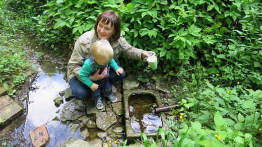 Lenka Kmošková ze Spolku archaických nadšenců s vnukem ochutnávají vodu ze studánky ve Vysokém lese