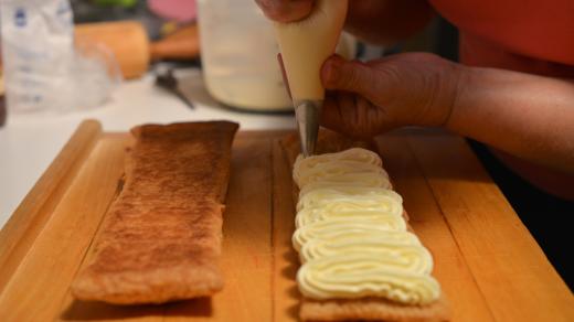 Vanilkovým krémem naplníme cukrářský sáček a každý druhý pruh upečeného listového těsta jím zcela pokryjeme