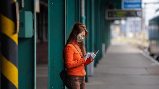 Mladá žena v roušce čeká v Pardubicích na vlak