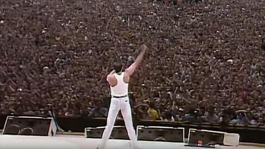 Freddie Mercury stojí před davem na londýnském stadionu ve Wembley.