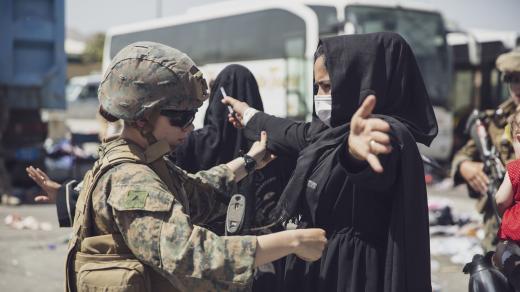 Příslušnické americké námořní pěchoty prohledává Afghánku na letišti v Kábulu