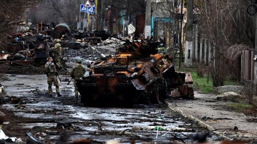 Voják pózuje u ruského zničeného tanku a obrněných vozidel ve městě Buča poblíž Kyjeva