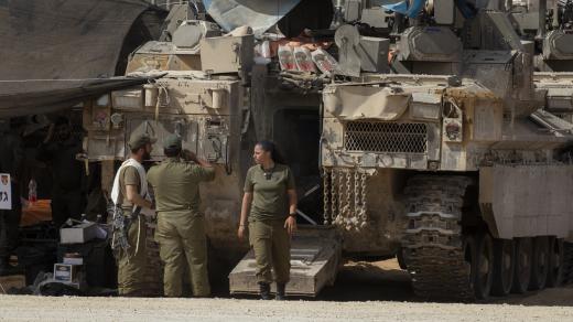 Příslušnice izraelské armády před obrněným transportérem v jižním Izraeli