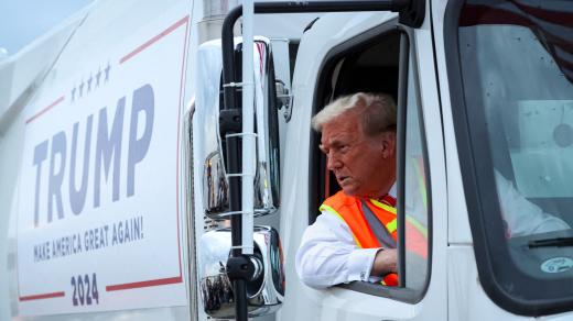 Donald Trump v popelářském kampaňovém voze a reflexní vestě na letišti v Green Bay ve Wisconsinu (30. října 2024)