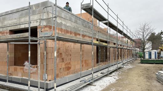 Hrubá stavba má zatím přízemí, dělníci pracují na prvním patře