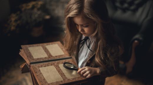 Dítě, dívka v převleku Sherlocka Holmese, fotoalbum, lupa, starý interiér