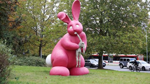 Socha obřího růžového králíka pojídajícího lidské tělo bez hlavy v Plzni od Adama Trbuška