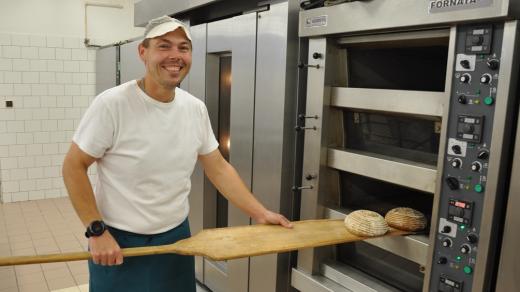 Pekař David Jeřábek vytahuje z pece upečený chléb